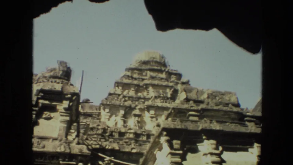 1974 8mm India footage shows a low-angle view of an ornate stone temple facade with pillars and layered carvings.
