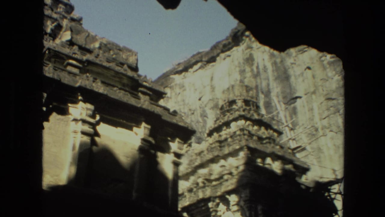 Weathered temple carvings and pale stone wall partly framed by shadow.