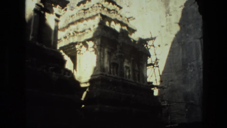 1974 India home-movie view of carved stone temple architecture, scaffolding, and strong sunlight falling across weathered ruins.