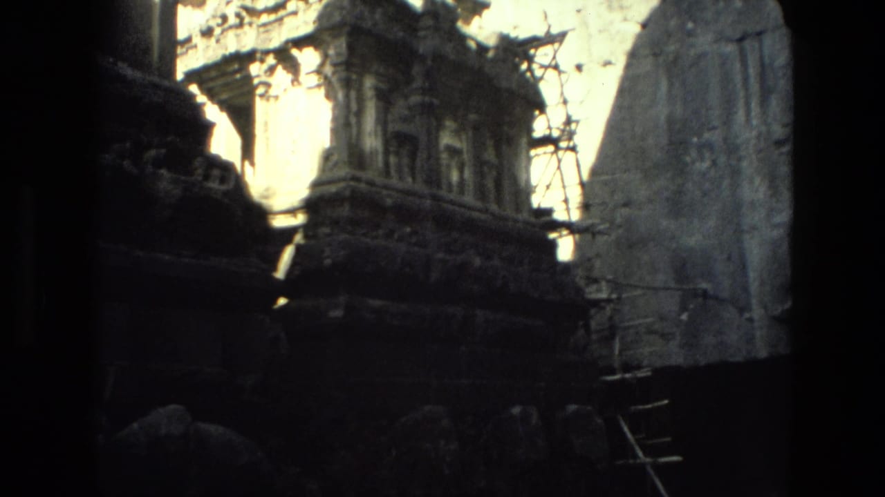 Carved stone temple tower and surrounding masonry with scaffolding in strong contrast.