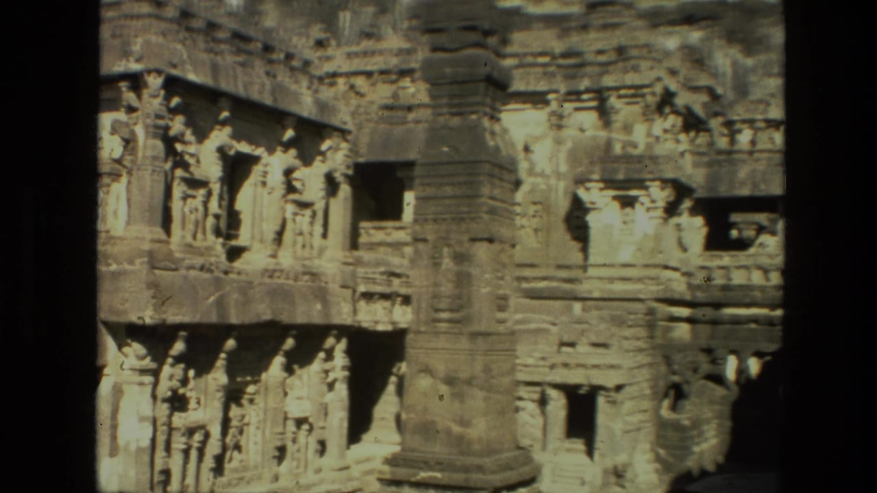 Stone temple carvings and a prominent pillar set into a rock face.