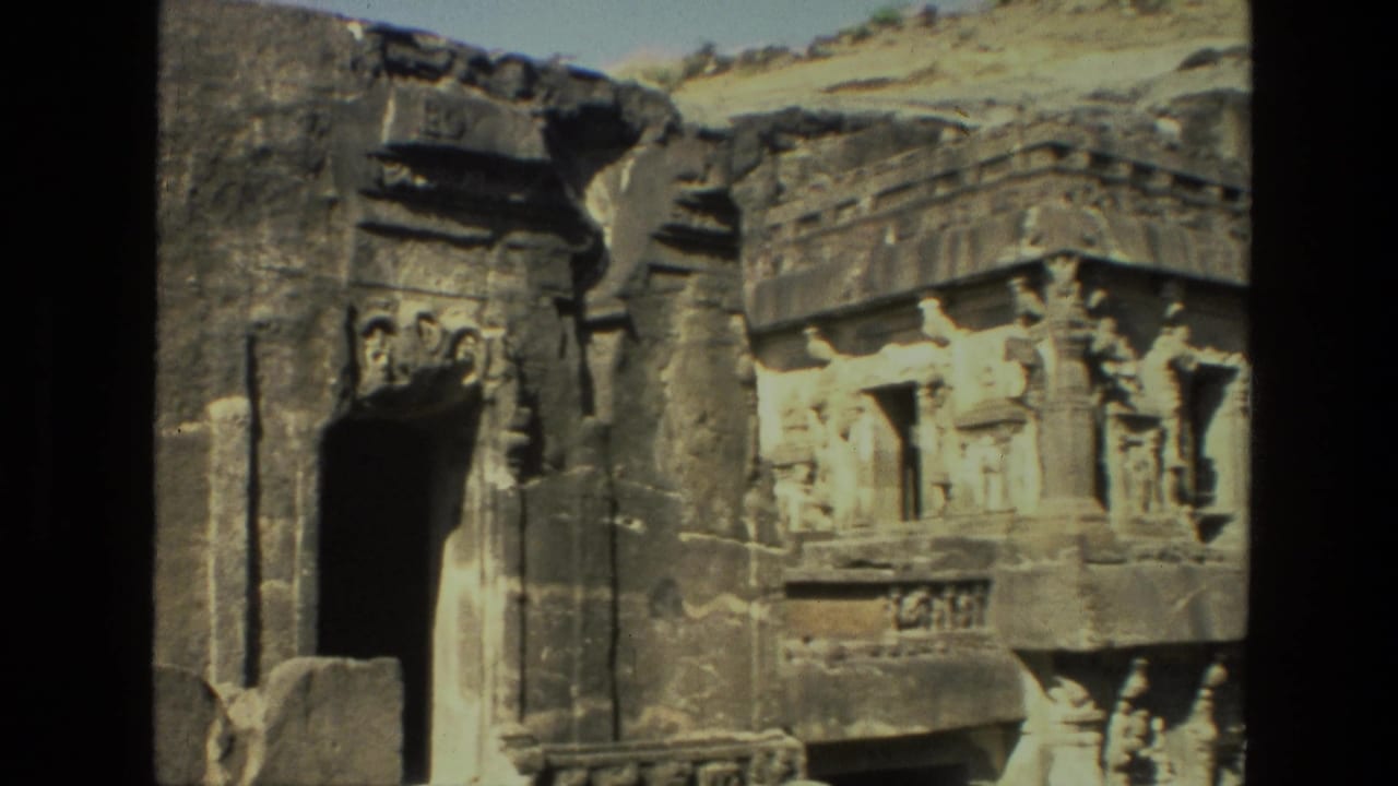 Rock-cut temple doorway with carved figures and weathered stone facade.