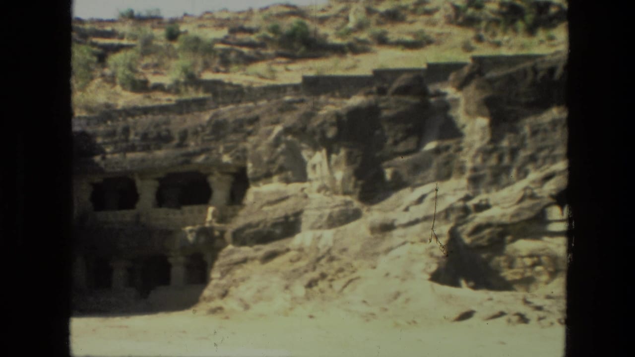 Cliffside cave openings and carved stone structures in bright sun.