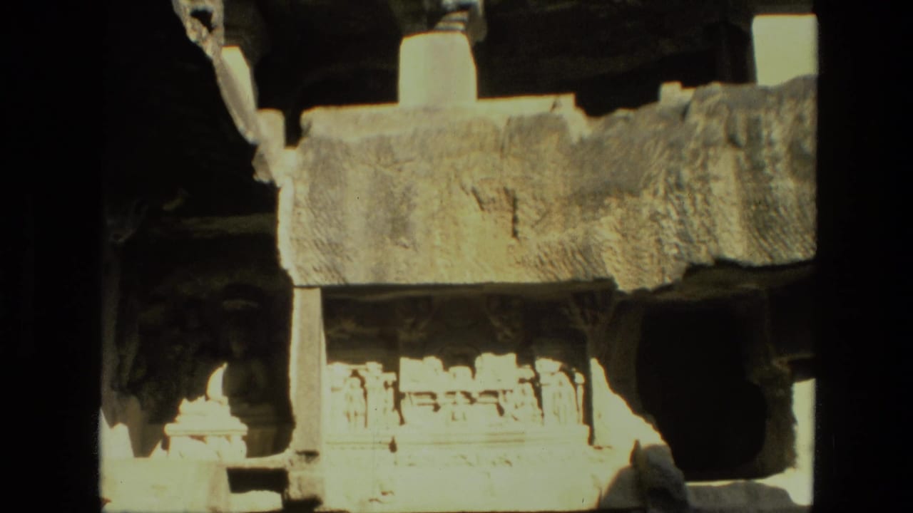 Close view of carved stone ledges and pale pillars inside shadowed rock architecture.