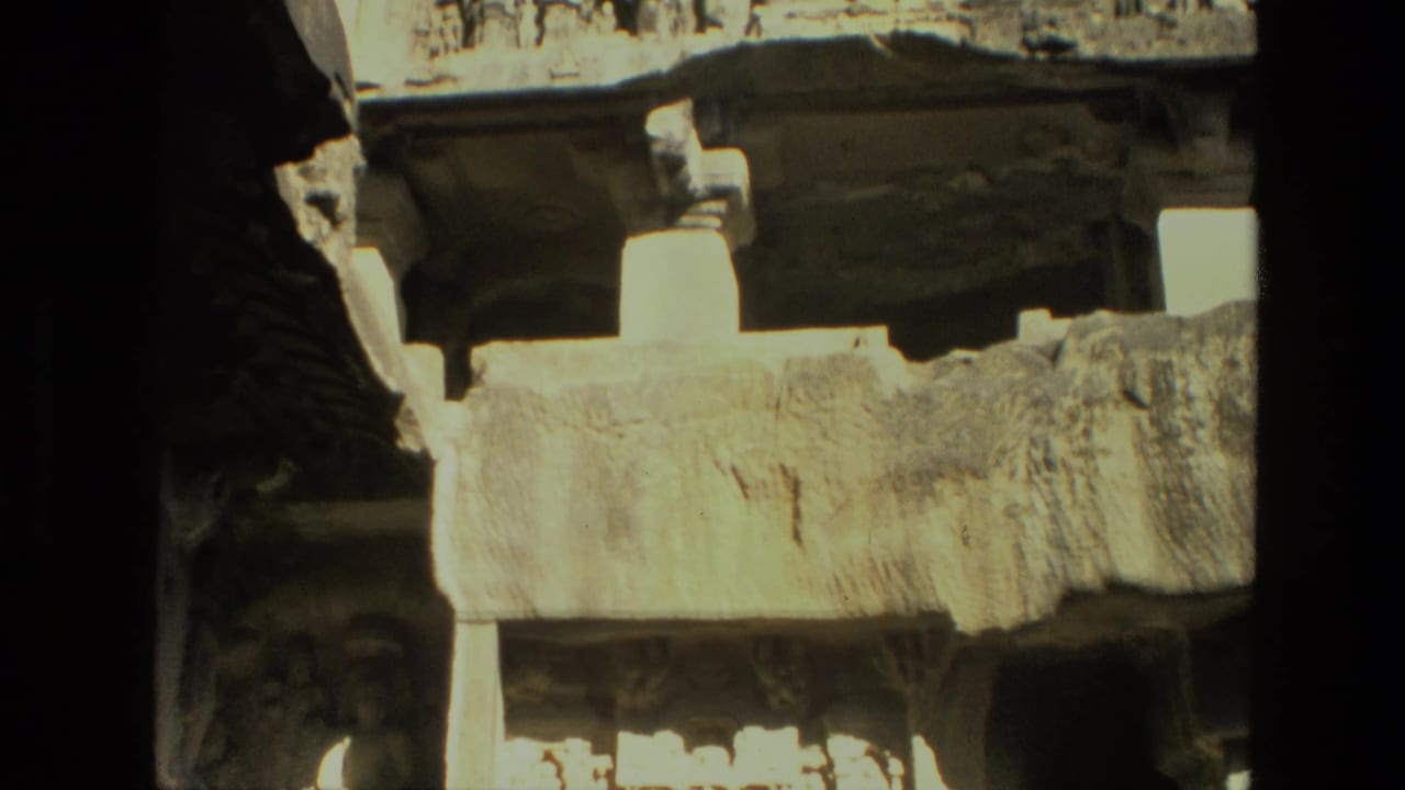 Weathered stone beam and pale pillar shapes framed by dark rock shadows.