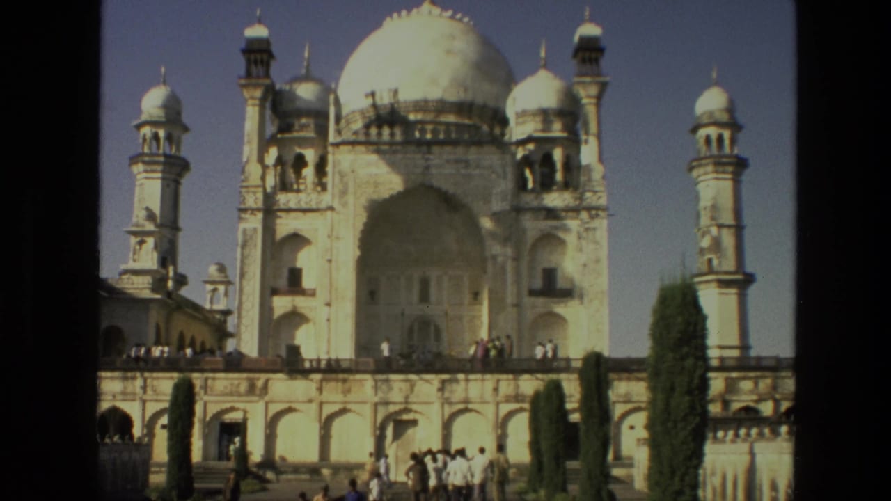 Closer view of the domed facade, minarets, terrace, trees, and visitors.