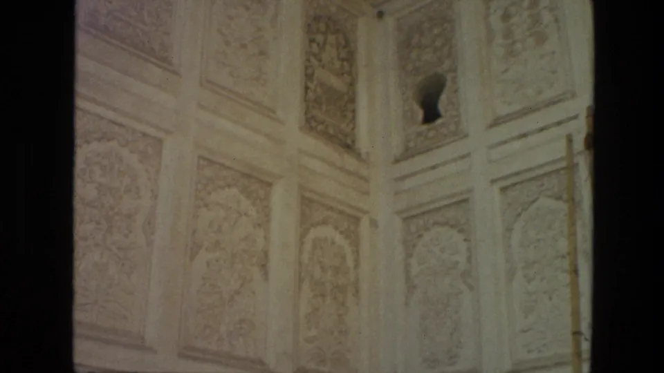 1974 India 8mm frame showing pale carved interior or wall surfaces with floral panels, an arched niche, and soft faded film exposure.