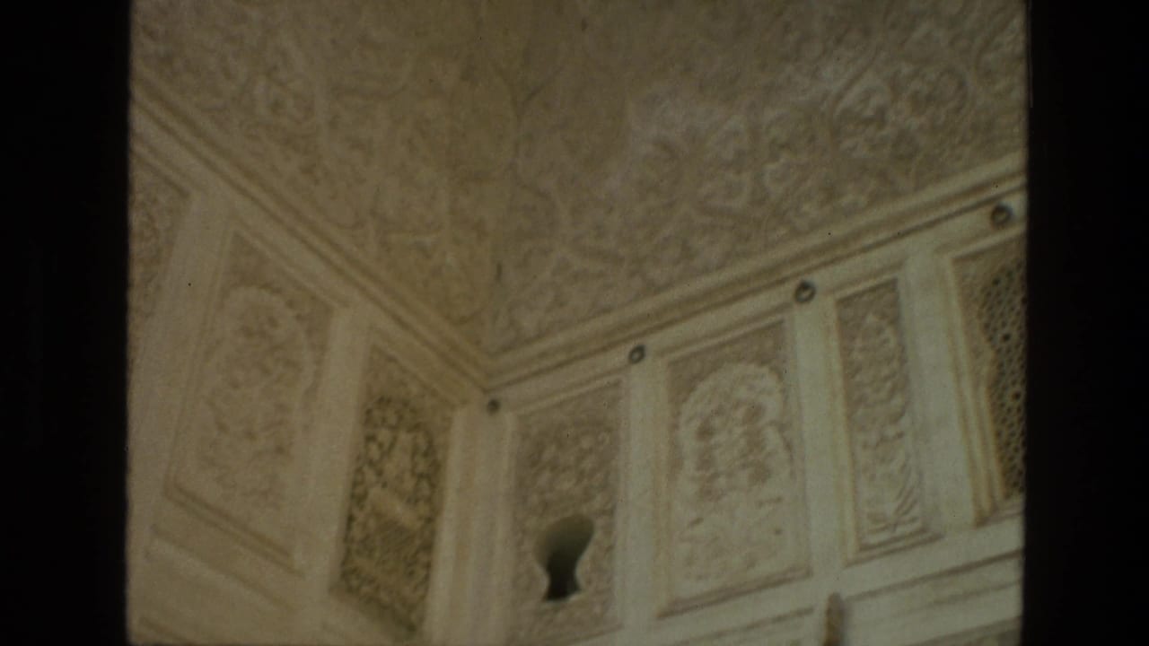 Ornate carved wall and ceiling corner with a small dark keyhole-shaped opening.