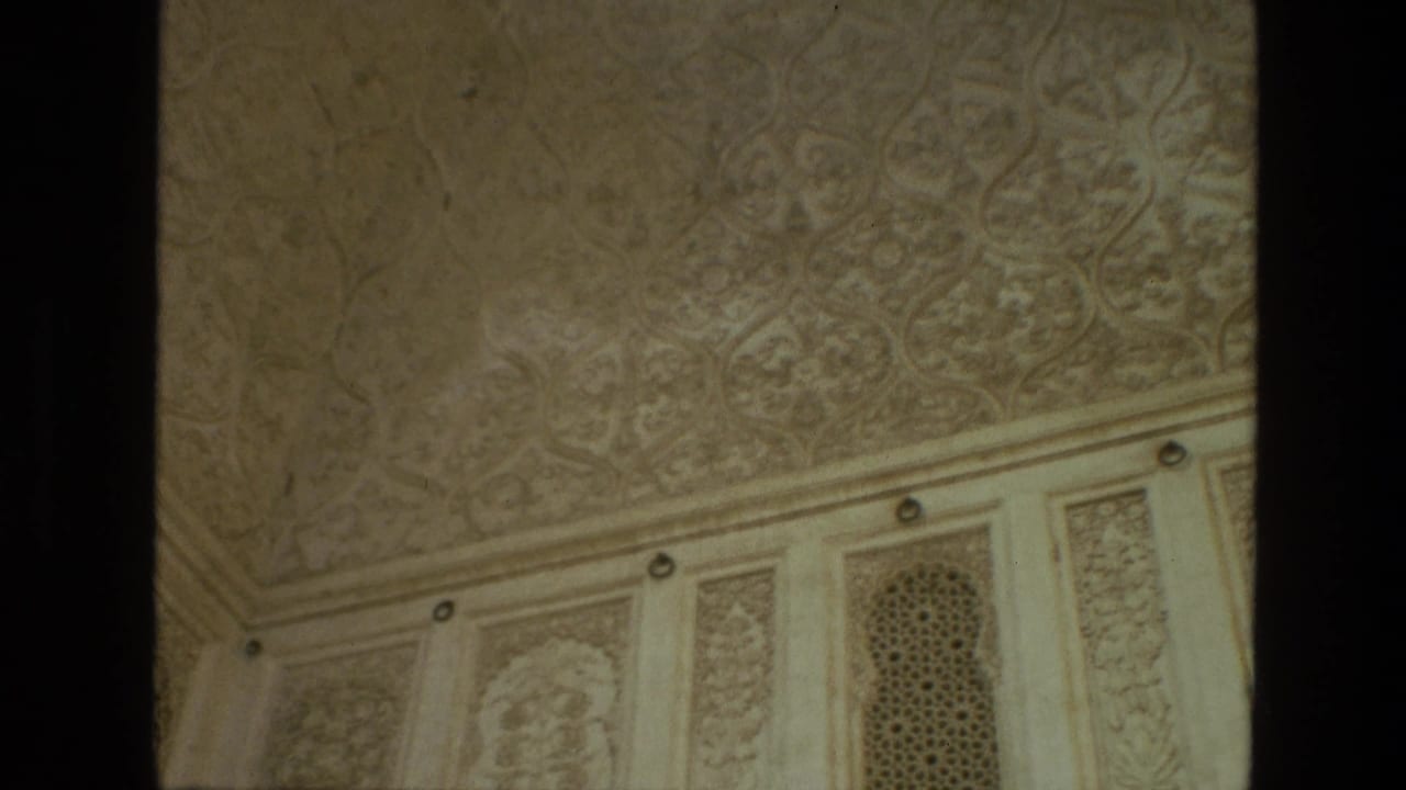 Carved ceiling and wall panels with an arched lattice screen in a pale interior surface.