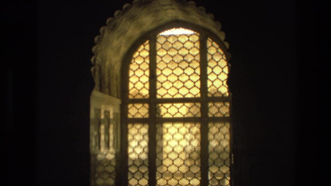 Warm arched lattice window glowing against a dark interior.