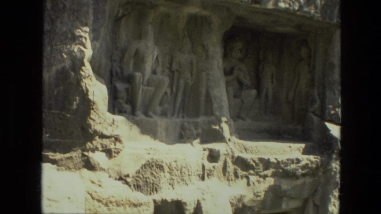 Weathered stone reliefs carved into a rock face beside a recessed opening.