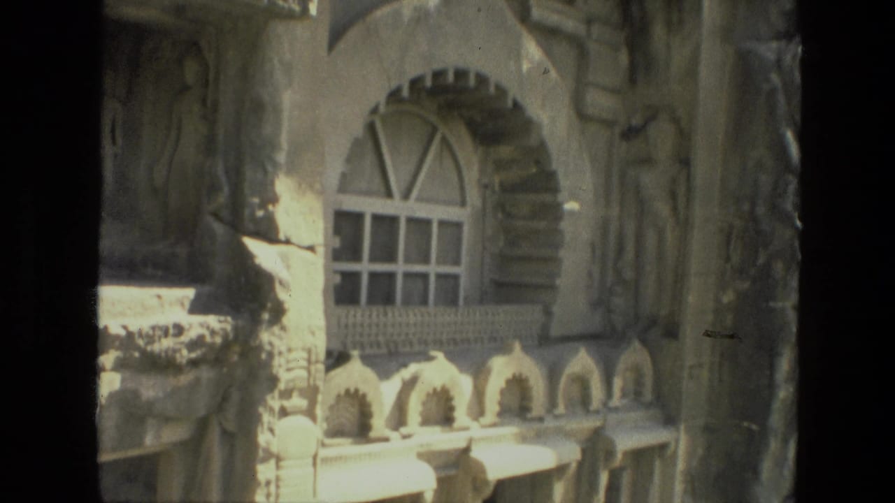 Arched window and carved stone details on a sunlit exterior wall.