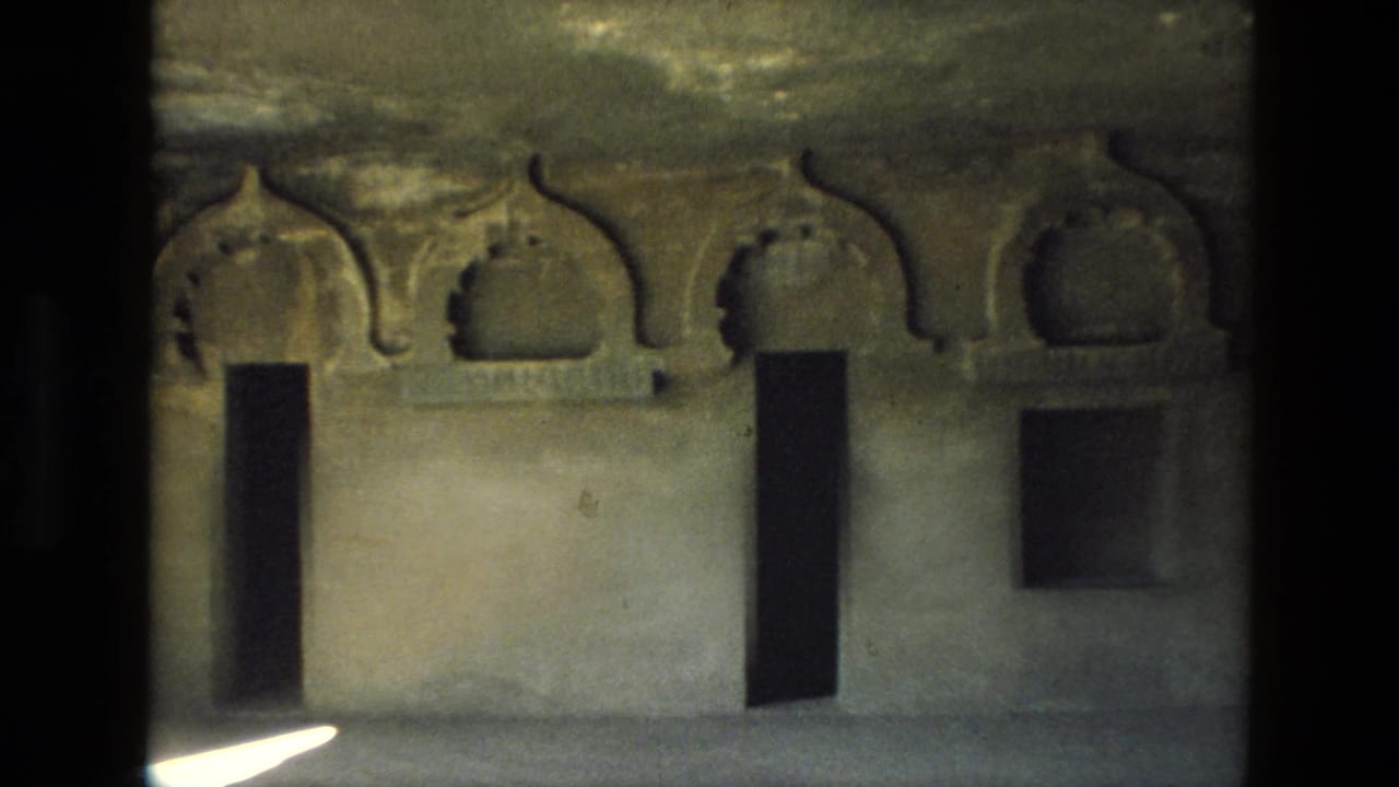 Dim stone wall with carved arched recesses and dark rectangular openings.