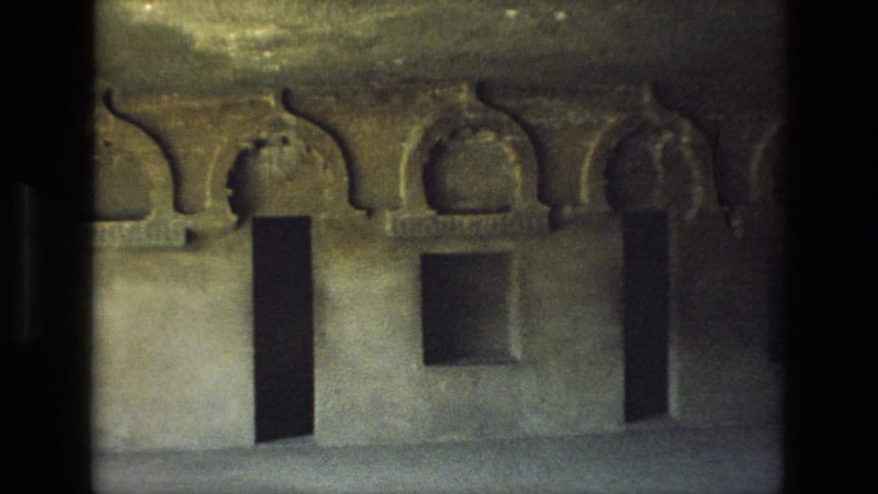 1974 8mm India view of weathered stone arches and rectangular recesses inside a likely historic cave temple.