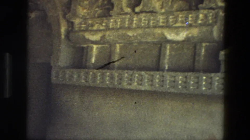 1974 8mm India cave-temple detail of a decorated stone ledge or cornice with block-like carvings and deep shadow.