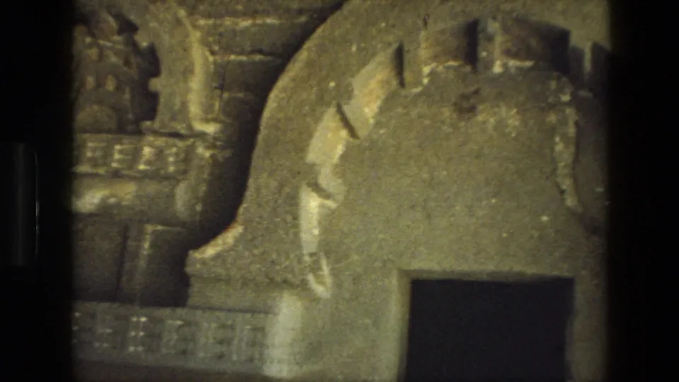 1974 India 8mm frame showing weathered rock-cut architectural forms, including curved stone edges and a dark doorway-like opening.