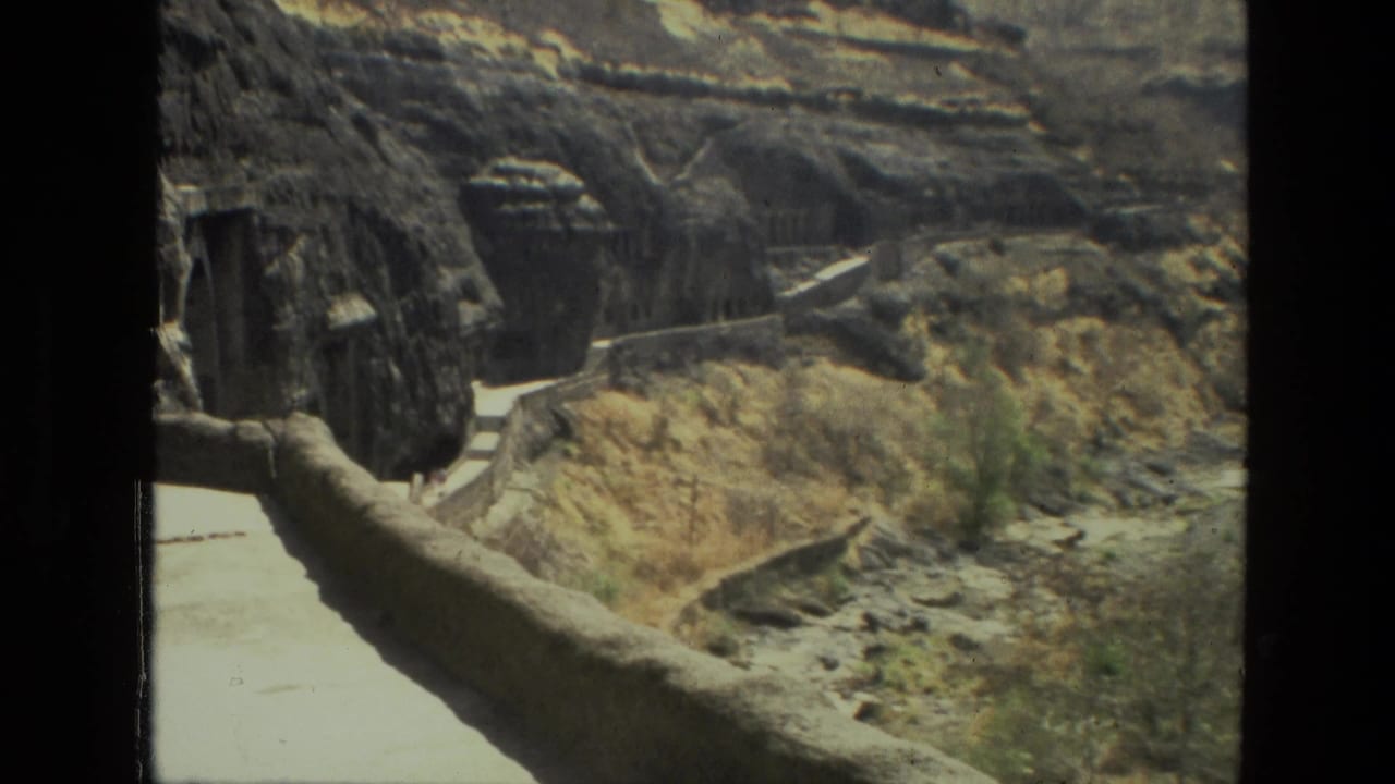 Visitor-shot 1974 India footage frames a stone walkway, steps and cave openings cut into rugged canyon rock.