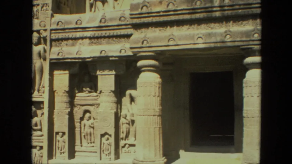 1974 India 8mm frame showing lower carved facade details, including columns, relief niches, sculptural figures, and a shadowed doorway.