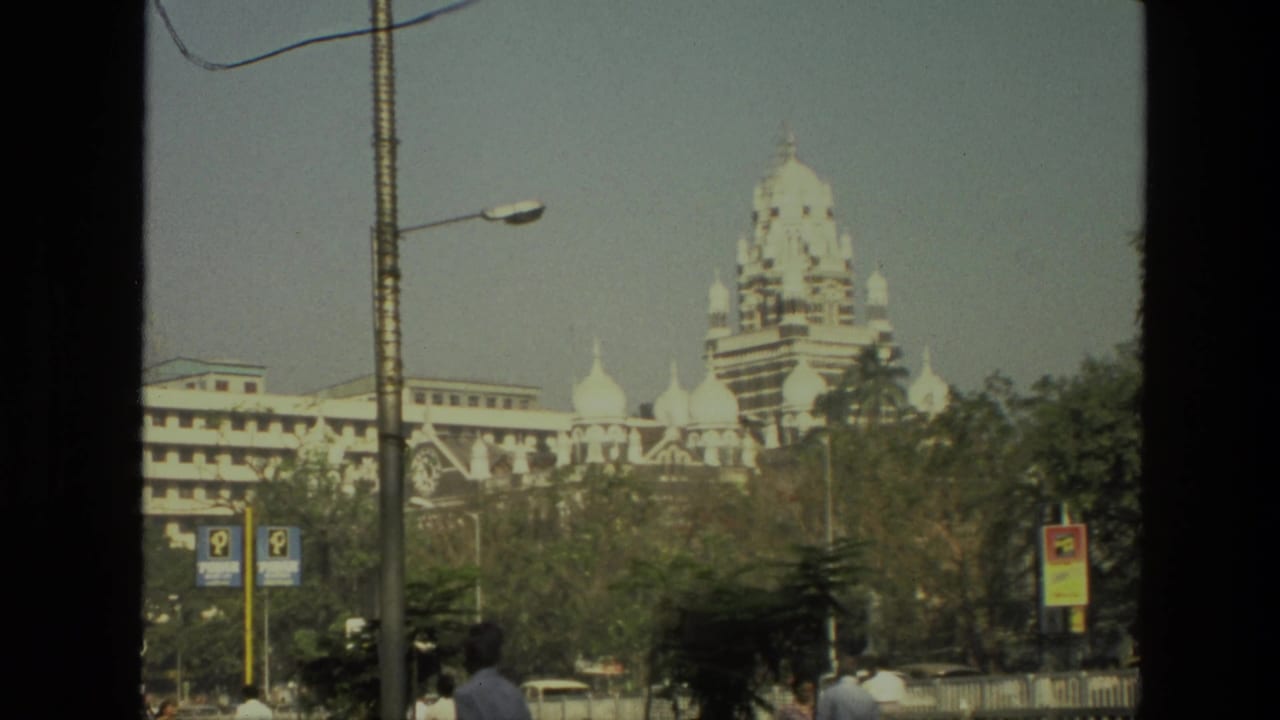 Large domed building behind trees with street lamps, signs, and pedestrians near the bottom of frame.