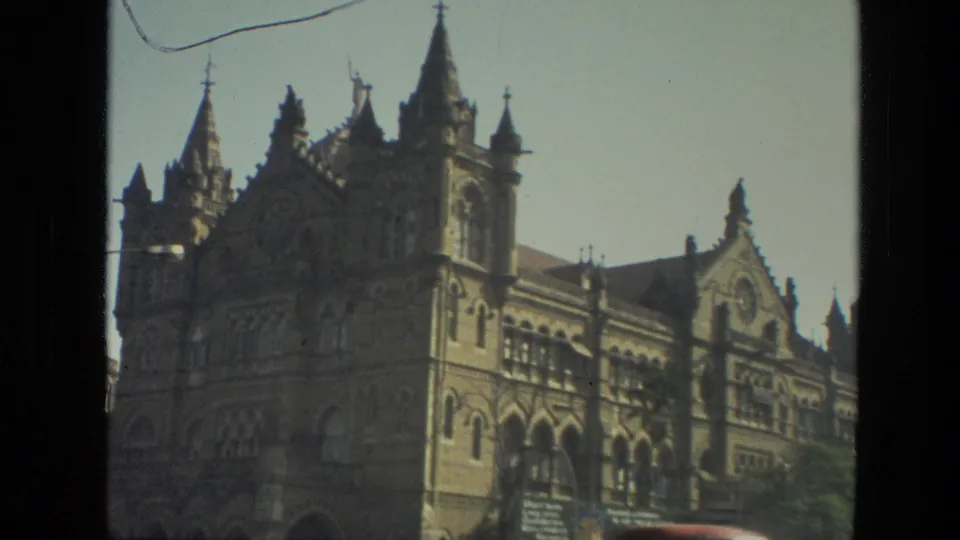 1974 Mumbai landmark exterior showing the ornate station facade, tower details, arched windows, and a passing street view.