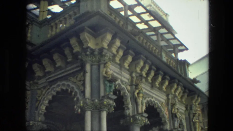 1974 India 8mm frame showing ornate arched architecture, carved capitals, columns, and a roof canopy from a close exterior angle.