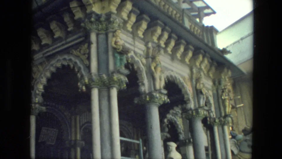 1974 India travel frame of a richly decorated exterior facade with arched openings, paired columns, carved capitals, and sculpted ornament.