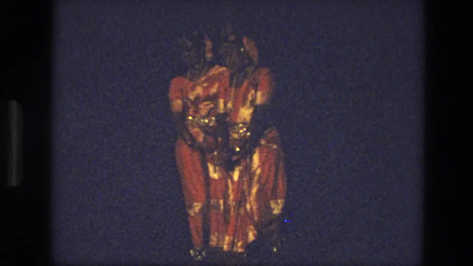 A closer 1974 India frame shows red-and-gold costumed performers clustered together, softened by motion blur and low stage light.