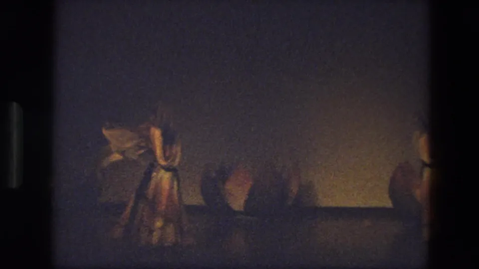 1974 India 8mm frame showing a dancer in a flowing costume and veil moving through a dimly lit stage scene.