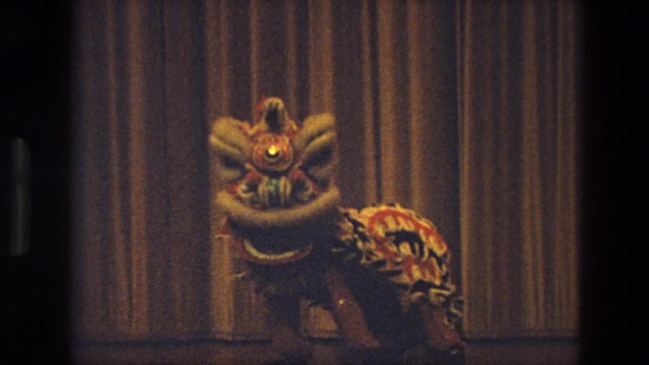 Closer 1974 India frame of a colorful lion dance costume with a bright eye in front of the stage curtain.