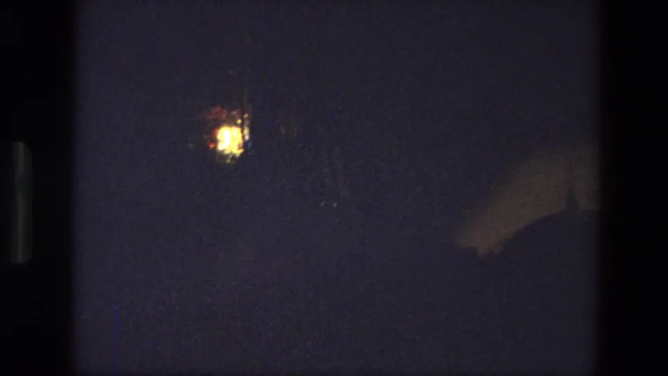 Low-light 8mm frame, likely from the same 1974 India reel, showing a small distant light against darkness.