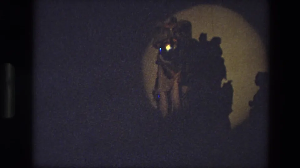 1974 India 8mm frame with a costumed performer and nearby figures visible in a warm stage spotlight.