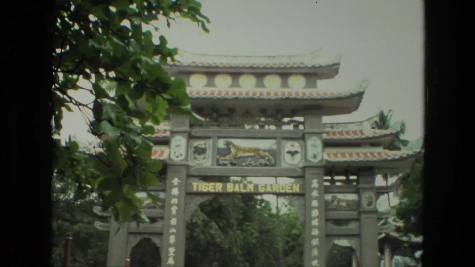1974 8mm India travel frame showing the Tiger Balm Garden entrance arch, tiger emblem, and surrounding leaves.