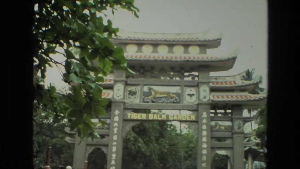 1974 8mm India travel frame showing the Tiger Balm Garden sign and ornate Chinese-style entrance framed by leaves.