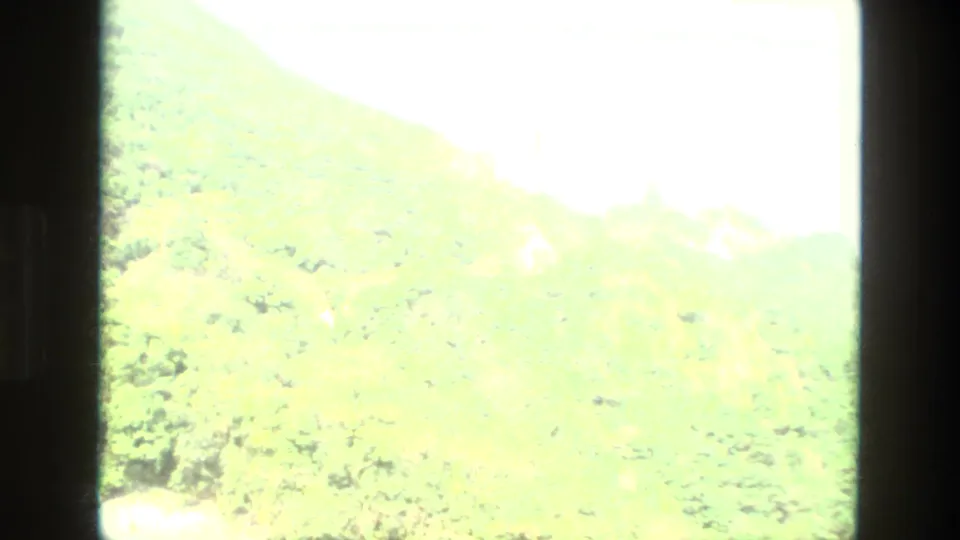 1974 India 8mm frame transitioning from the interior sequence to a bright, overexposed green hillside view.