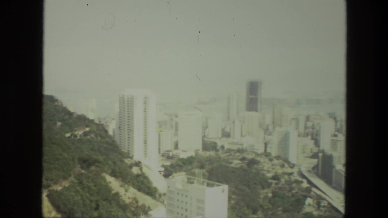 Hillside and city towers with a dark vertical film-frame divider.