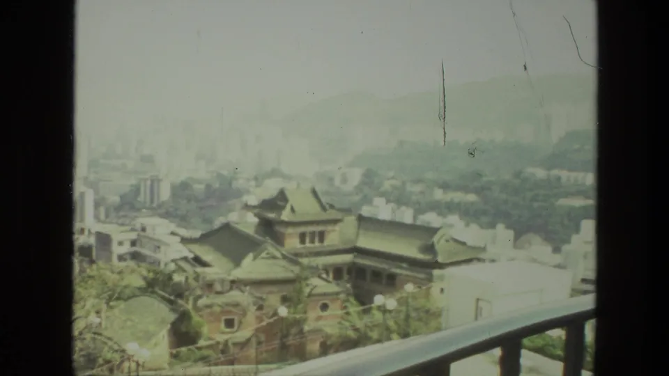 1974 8mm India footage appears to show a hazy city skyline from a high balcony, with traditional roofs below distant high-rises.