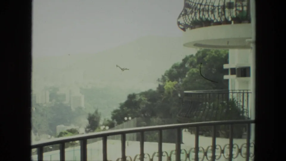 End frame of a 1974 India balcony view, showing a misty urban valley, trees and distant tower blocks.