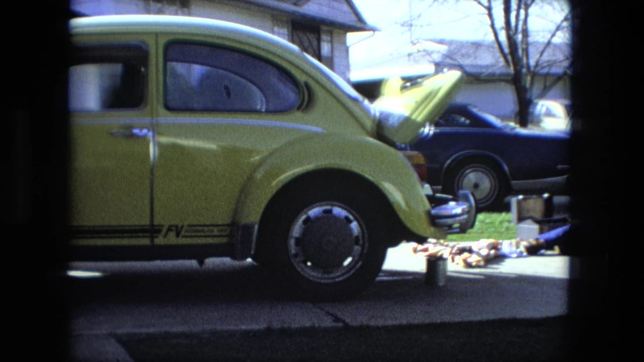 Yellow Volkswagen Beetle parked with its front hood open beside tools in a suburban driveway.
