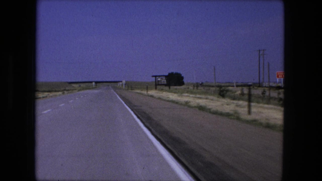 Moving 8mm view along a rural highway near Fort Wayne, Indiana, with a bridge ahead and roadside signs to the right.