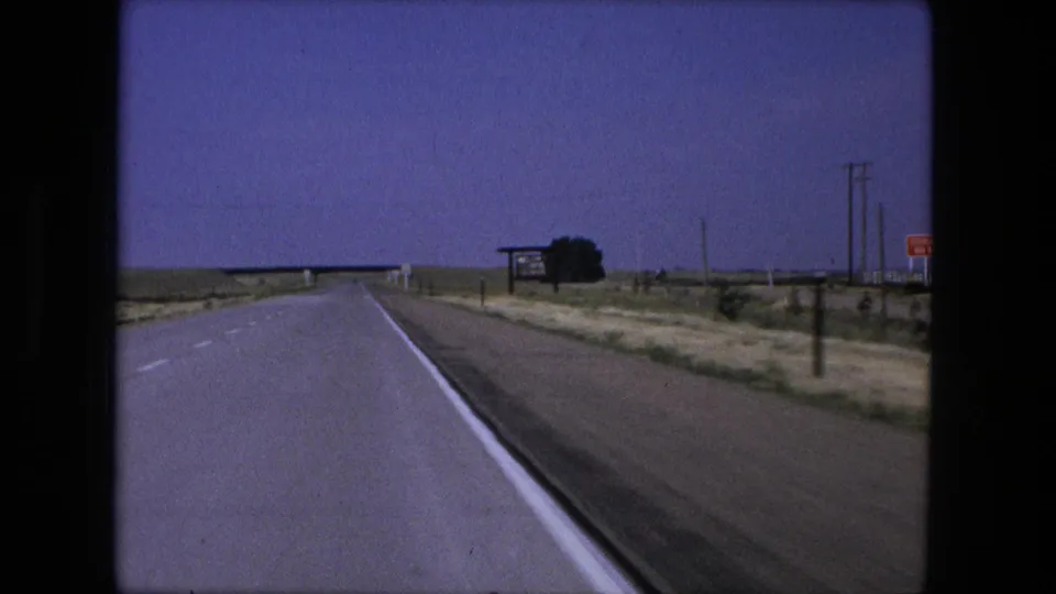 Moving 8mm view along a rural highway near Fort Wayne, Indiana, with a bridge ahead and roadside signs to the right.