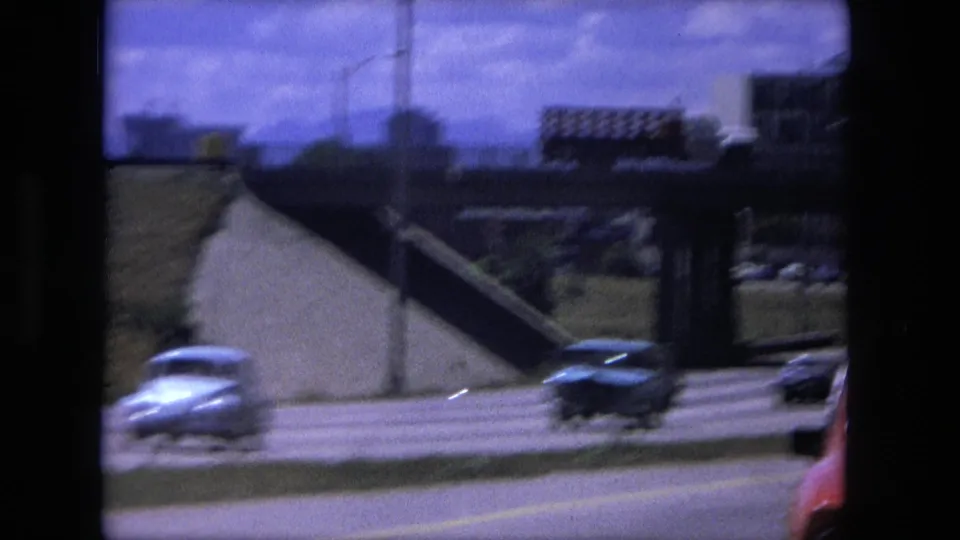 1976 Fort Wayne highway view with cars, an overpass or bridge structure, and a distant truck or lorry.