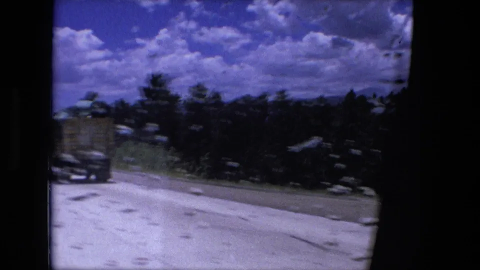 A passing truck appears beside the highway in this 1976 Fort Wayne, Indiana 8mm travel frame with trees and bright clouds.