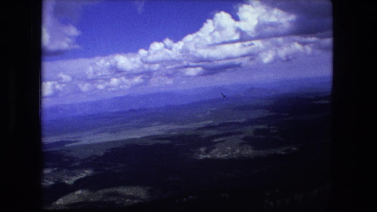 Distant mountain ridges and valley beneath a blue sky with large clouds.