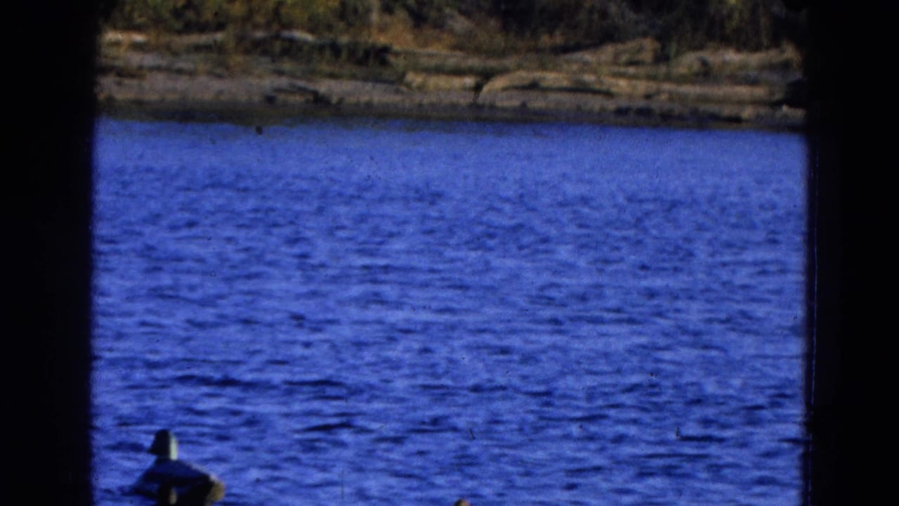 Blue lake water with a distant shore and dark film-frame borders.