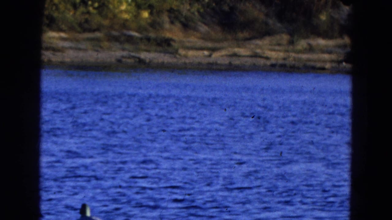 1968 Diller, Nebraska 8mm frame with rippled blue water, a far shoreline, and heavy dark contact-sheet borders.