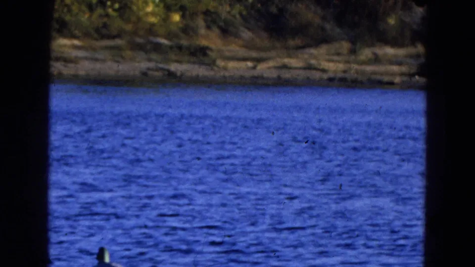 1968 Diller, Nebraska 8mm frame with rippled blue water, a far shoreline, and heavy dark contact-sheet borders.