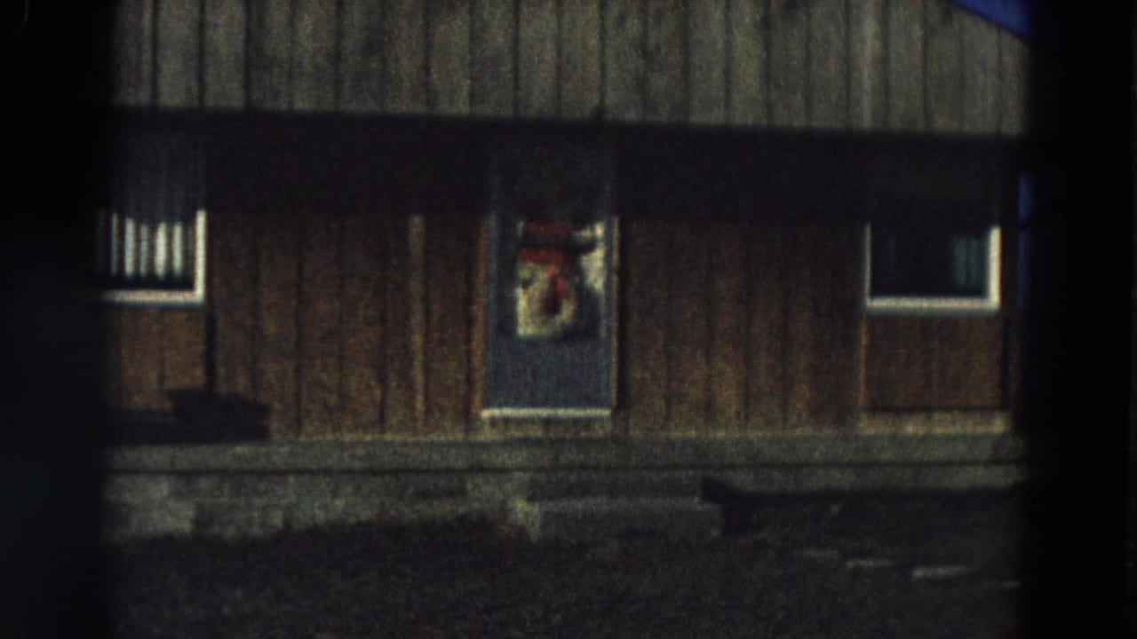Dark-framed view of a wooden house exterior with a decorated central door.