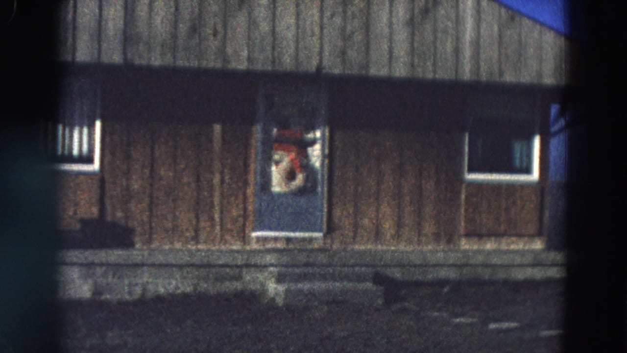Wood-sided building with blue door, small windows, and soft home-movie focus.