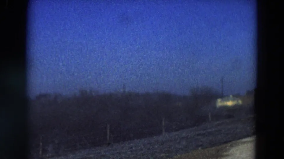 1968 Diller, Nebraska frame looking across an open rural field with a distant bright sign or structure near the horizon.