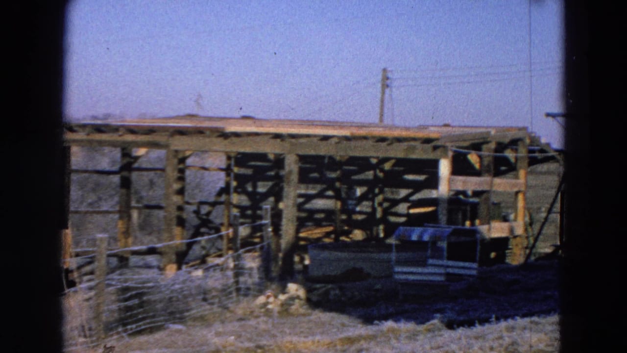 1968 Diller, Nebraska frame showing an open wooden barn or shed frame with a small animal shelter and power lines behind it.